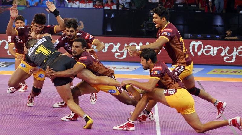 U.P. Yoddhas players make an unsuccessful attempt to pin down Telugu Titans captain Rahul Chaudhari, in black jersey during the match. (Photo: AP)