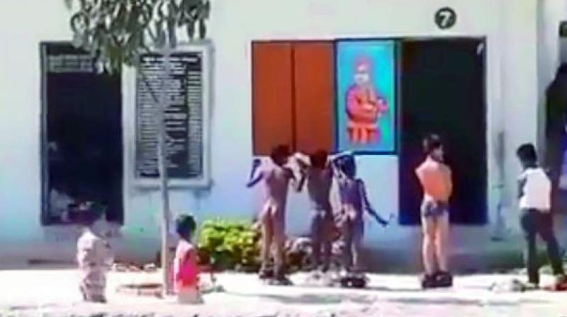 Videograb shows the students made to stand naked in the sun by the teachers as punishment.