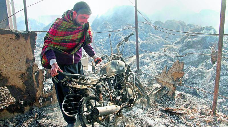 A villager looks at his charred motorbike after shelling by the Pakistani forces, at Jora Farm village, on Sunday.  (Photo: PTI)
