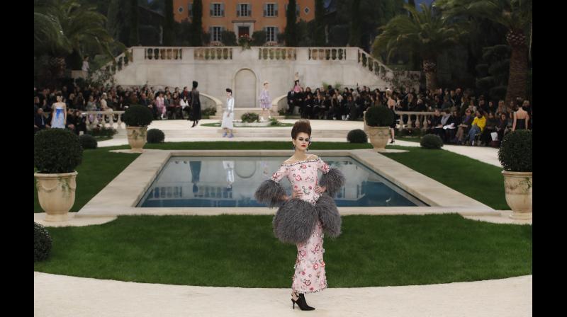 The manicured gardens with potted shrubs, real growing grass and palm trees beautifully sculpted the catwalk. (Photo: AP)