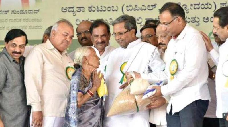 A file photo of CM Siddaramaiah distributing foodgrains to a beneficiary of Anna Bhagya scheme.