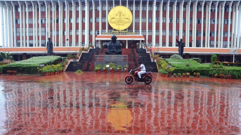 Soaked in rain: A watch and ward staff braves the morning showers in front of the Assembly complex even as the session started on a stormy note inside on Monday.	(Photo: Peethambaran Payyeri)