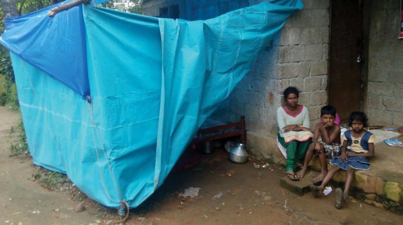 Manjula along with her two kids near their house attached by the bank. Their temporary shelter of plastic sheets is also seen.