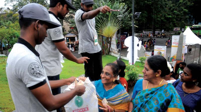 Green Army volunteers put labels on plastic carry bags and bottles, which would be returned to the visitors when they leave Kanakakkunnu ground. A scene on Tuesday. (Photo: A.V. Muzafar)