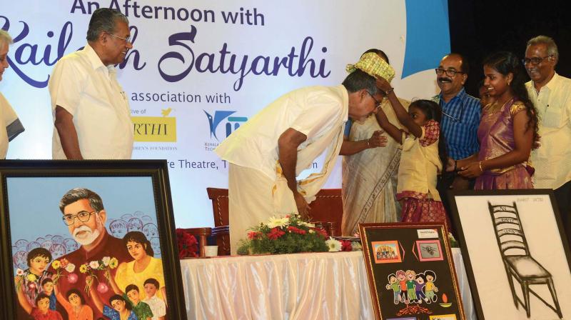 Children present a cap made using palm leaves, to Nobel laureate Kailash Satyarthi during a reception accorded to him in Thiruvananthapuram on Tuesday. Chief Minister Pinarayi Vijayan is also seen.	(Photo: Peethambaran Payyeri)