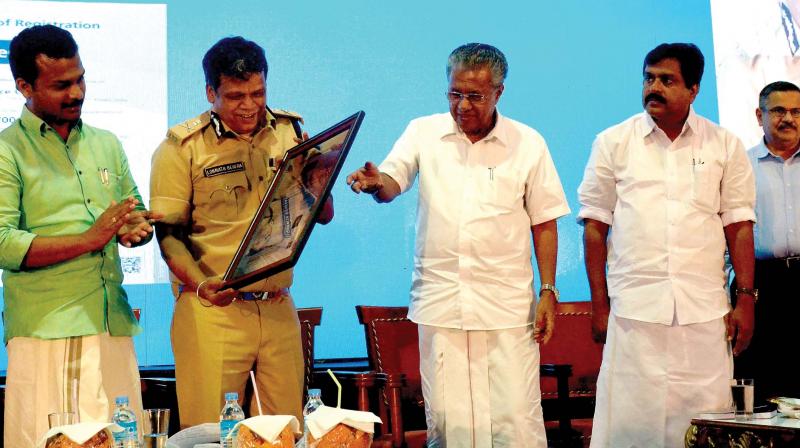 State police chief Lokanath Behera curiously watches the ISO certificate issued to Cyberdome. Chief minister Pinarayi Vijayan looks on. (Photo: DC)