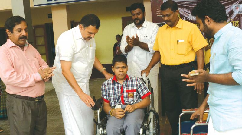 K Muraleedharan, MLA, presents a motorised wheel-chair to Ananthan, a physically-challenged student of Kendriya Vidyalaya, Pattom, in Thiruvananthapuram on Monday. Principal S. Ajayakumar, KSU state secretary Eric Stephan look on.	(Photo: DC)