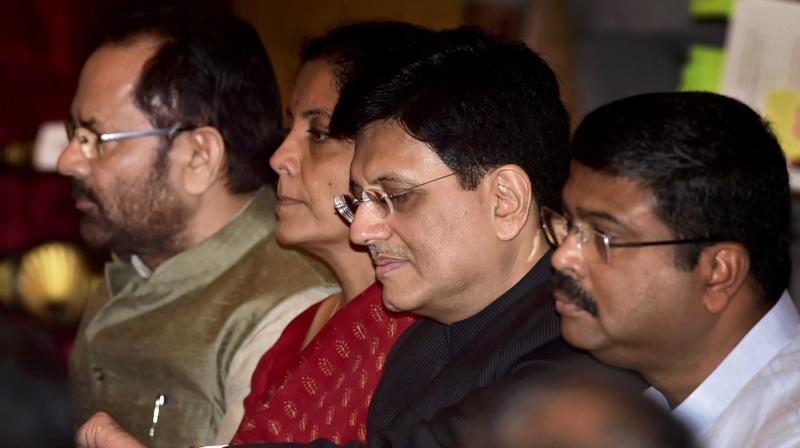 Cabinet Minister Piyush Goyal checks time in his wrist watch as he waits with cabinet colleagues Nirmala Sitharaman, Mukhtar Abbas Naqvi and Dharmendra Pradhan for the swearing in ceremony at Rashtrapati Bhavan in New Delhi on Sunday. (Photo: PTI)