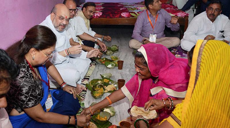 BJP President Amit Shah with Rajasthan Chief Minister Vasundhara Raje having lunch at Dalit Family during his three day visit in Jaipur on Sunday. (Photo: PTI)