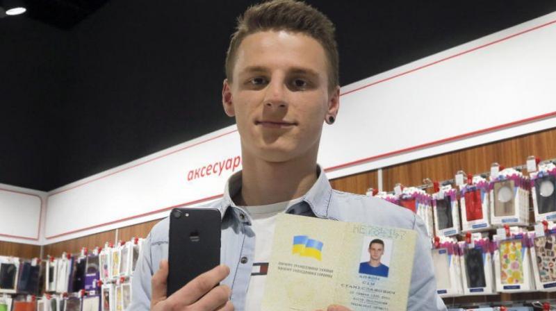 A young man shows his passport giving his name as iPhone Sim (seven), and a new iPhone 7 in an electronics shop in Kiev, Ukraine, Friday, Oct. 28, 2016. (Photo: AP)