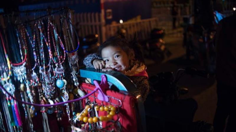 A girl plays on a souvenir vendors cart in the regional capital Lhasa, in Chinas Tibet Autonomous Region. The traditional teahouses and fashion boutiques of Bayi are the among the liveliest districts of Lhasa, and owned and patronised by both Tibetans and Han Chinese. But some say increasing prosperity is just Beijing buying peace. (Photo: AFP)