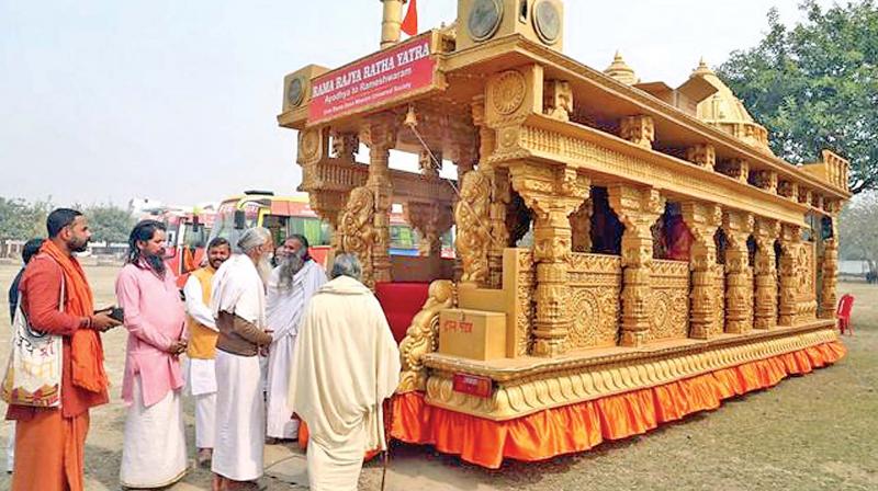 Sadhus admiring the Ayodhya-Rameswaram Rama Rajya Ratha Yatra, a chariot modelled on the proposed Ram Janma Bhoomi Temple, at Karsevakpuram in Ayodhya a day before its launch on March 13. (Photo:  PTI)