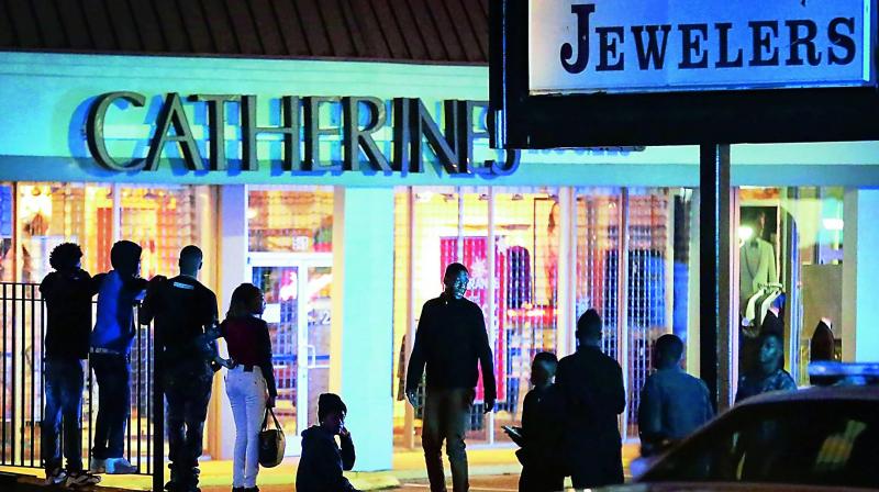 People linger in the parking lot around a mall after it was closed due to a disturbance 	(Photo: AP)