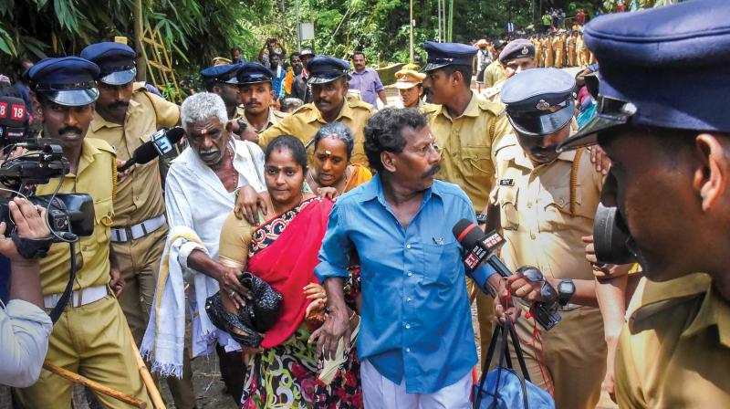 Police escorts Madhavi (of Andhra Pradesh) and her family members after she was heckled by protesters while proceeding to Sabarimala temple on its  opening day on Wednesday. 		PTI