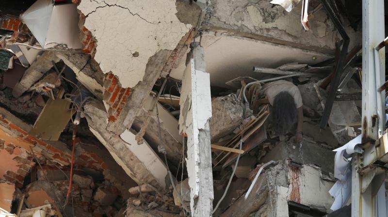 The body of woman hangs crushed by a collapsed building in the neighborhood of Roma Norte, in Mexico City. (Photo: AP)