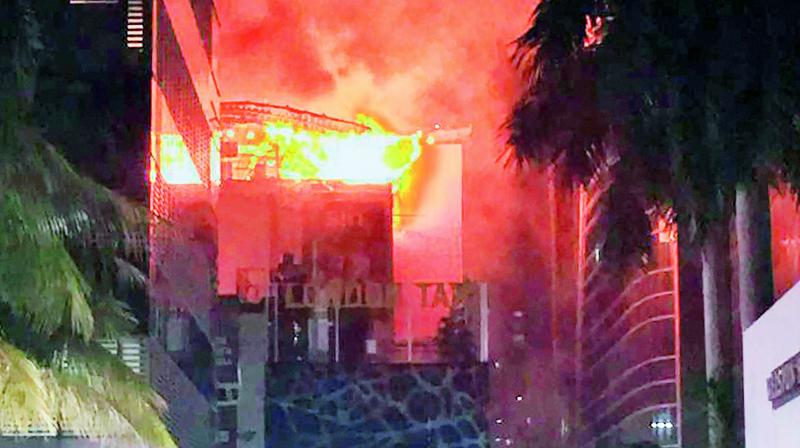 People mill around as a fire rages in two pubs located in the Trade House Building in Kamala Mills compound in Lower Parel late on Thursday night. (Photo: PTI)