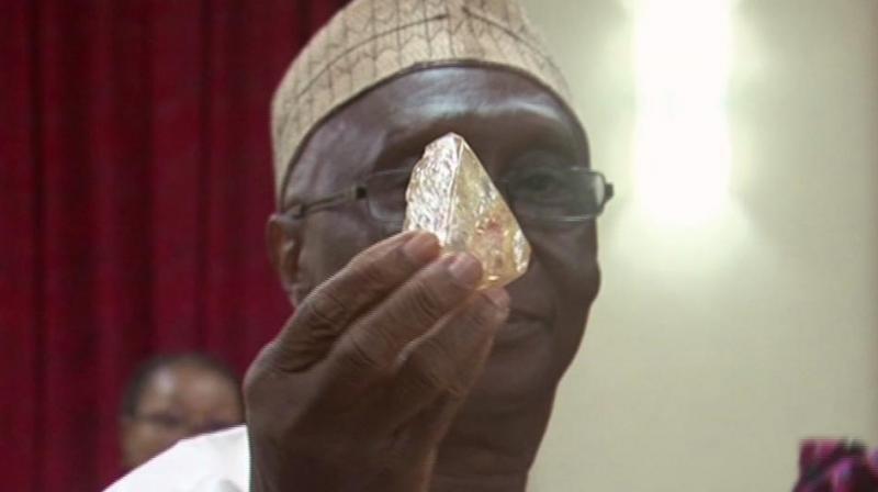 In this photo taken from video footage, Sierra Leones Minister of Mines and Mineral Resources Alhaji Minkailu Mansaray hands a diamond during a meeting with delegates of Kono district, where the gem was found, at the presidential office in Freetown, Sierra Leone. (Photo: AP)