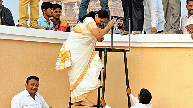 BJP leader Shobha Karandlaje climbs a ladder to watch Pancharathotsav in Nanjangud on Friday. (Photo: KPN)