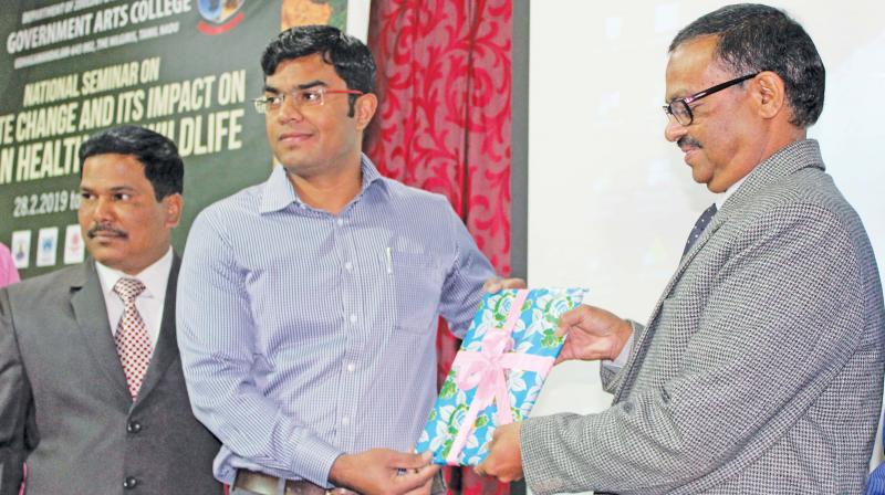 Sumesh Soman, District Forest Officer of Nilgiris, releases a souvenir during the inauguration of the national seminar on Climate change and its impact on human health and wildlife. (Photo: DC)