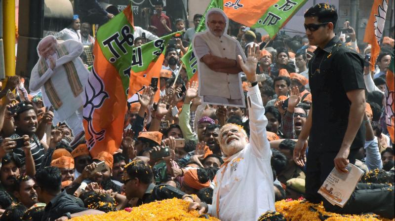 Prime Minister Narendra Modi greets at the crowd during a roadshow, in Varanasi on Saturday. (Photo: PTI)
