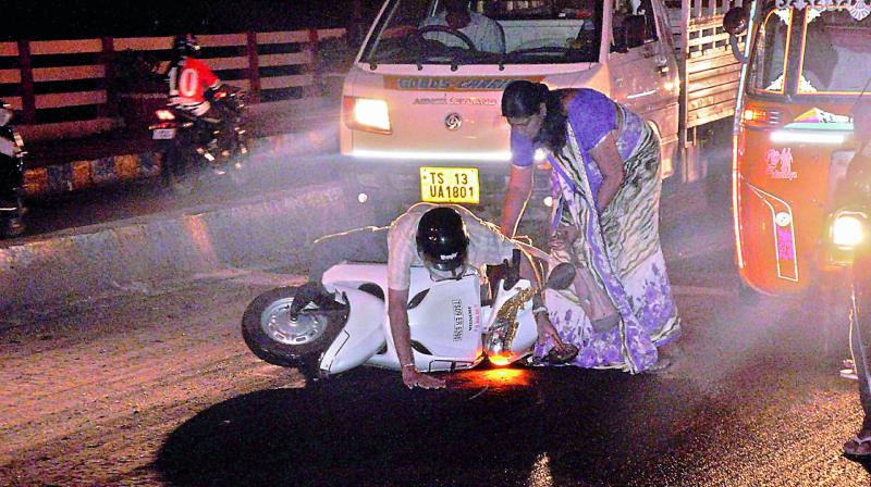 A woman helps a two-wheeler rider whose vehicle skidded during rain at Salar Jung Museum. (Photo: INN)