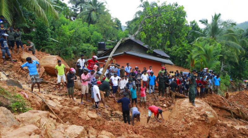 ri Lankans watch military rescue efforts at the site of a landslide in Bellana village in Kalutara district, Sri Lanka