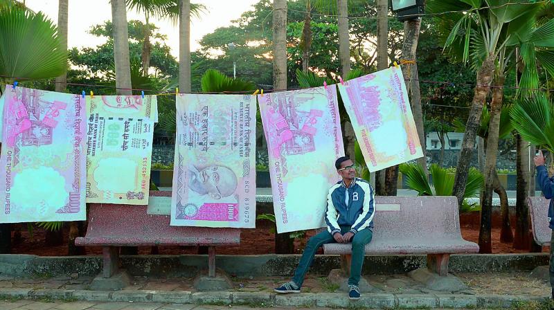 A man poses for a photo with replica prints of the demonetised 500 and 1000 rupee notes as part of a street art exhibition in Mumbai on Sunday. (Photo: AFP)