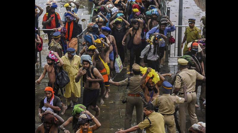 Devotees enter the Sabarimala temple as it opens amid tight security on Friday. (Photo: PTI)