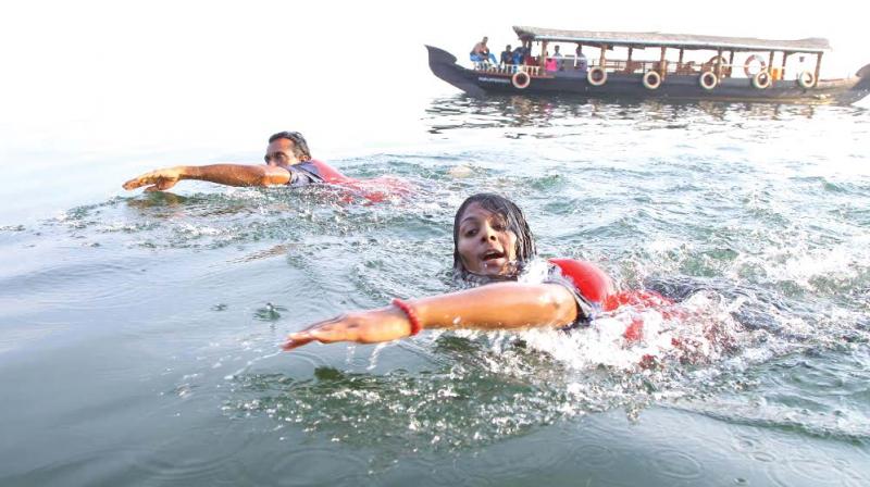 Malu Shaika swimming across Vembanad Lake accompanied by her trainer Saji Valasseril. (Photo: DC)
