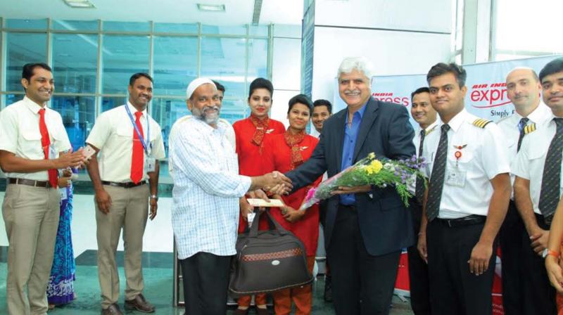 Air India Express CEO K. Shyam Sundar greets Mayinkutty, who received the first boarding pass.