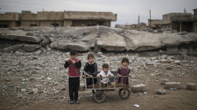 Children wait as their mother collects food being distributed in a neighborhood recently retaken by Iraqi security forces during fighting against Islamic State militants on the western side of Mosul, Iraq. (Photo: AP)