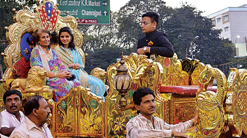 Mysuru Maharani Pramoda Devi Wadiyar, Maharaja Yaduveer Krishnadatta Chamaraja Wadiyar and his wife Trishika Kumari Wadiyar being taken out in a procession on a chariot during Chamarajpet 125 Utsav in Bengaluru on Saturday. (Photo: KPN)