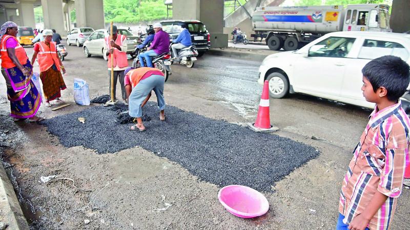 12-year-old Ravi Teja observes workers repair a patch of the Uppal - Habsiguda road on Wednesday. (Photo: Deccan Chronicle)