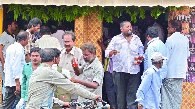 People buy liquor bottles at a shop in Bandar Road as officials closed some wine shops on the National and State Highways in Vijayawada on Saturday. (Photo: DC)