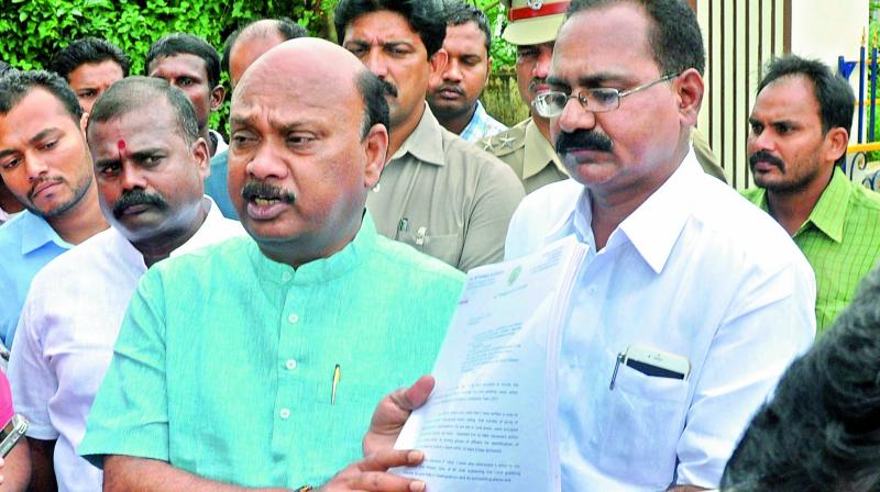 R&B Minister, Ch Ayyanna Patrudu displays the files after coming out of SIT office near AU Engineering College in Visakhapatnam on Friday. (Photo: DC)