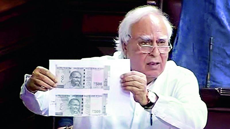 Congress leader Kapil Sibal shows photocopies of the two kinds of 500 notes in the Rajya Sabha in New Delhi on Tuesday. (Photo: PTI)