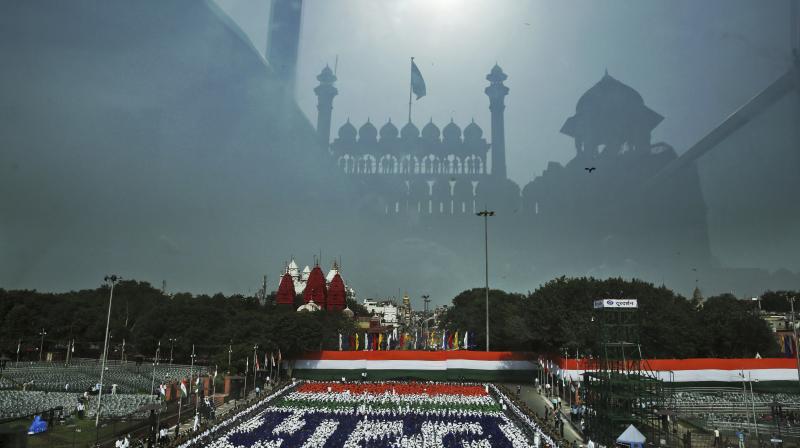Red Fort monument is reflected on the bullet proof glass covering the podium from where Indian Prime Minister Narendra Modi is scheduled to deliver an Indian Independence Day speech as schoolchildren wearing different colors form a representation of the national flag during a dress rehearsal for Independence Day celebrations in New Delhi, India. (Photo: AP)