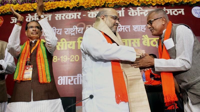 BJP National President Amit Shah being welcomed by the partys Madhya Pradesh unit president Nandkumar Singh Chauhan as Chief Minister Shivraj Singh Chauhan looks on, during a party meeting in Bhopal on Friday. (Photo: PTI )