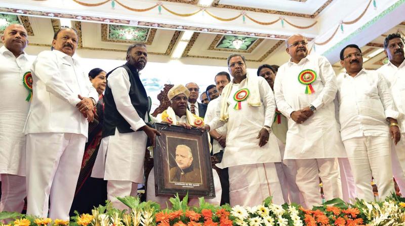 Chief Minister Siddaramaiah honours veteran Congress leader Mallikarjun Kharge with Devaraj Urs Award at a function to mark the 102nd birth anniversary of the former CM in Bengaluru on Sunday. (Photo: DC)