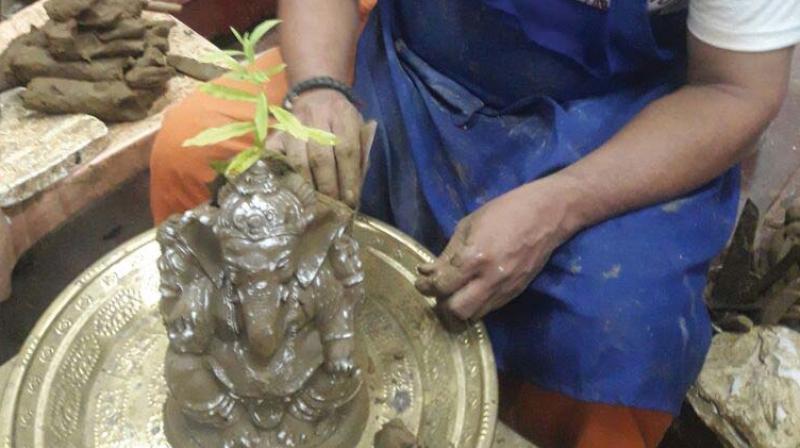 Final touches being given to the Ganesha idol with a sapling inside it.