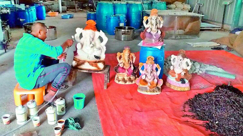 The organic paint made with leaves, barks, roots, seeds, pods of trees being being spray painted onto clay Ganesh idols.