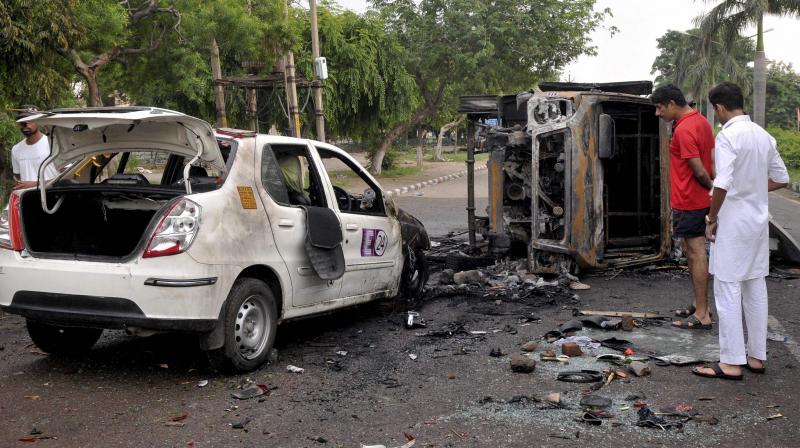 Charred vehicles lying on a road which were torched during violence triggered by the conviction of Dera Sacha Sauda head Gurmeet Ram Rahim Singh in a rape case. (Photo: PTI)