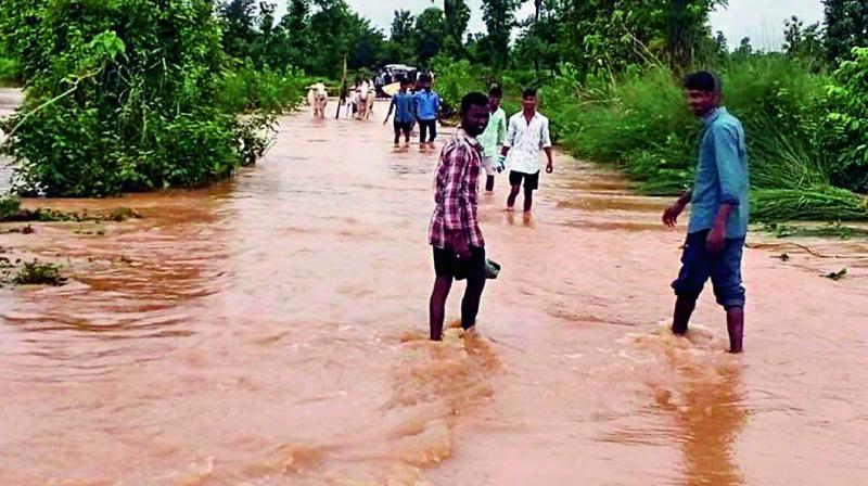 People have a tough-time to wade through the overflowing road culvert near Parvathipuram in Vizianagaram district on Monday. (Photo: DC)