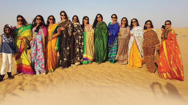 The group proves that sarees are easy to wear by donning them and walking in the sand dunes of Dubai.