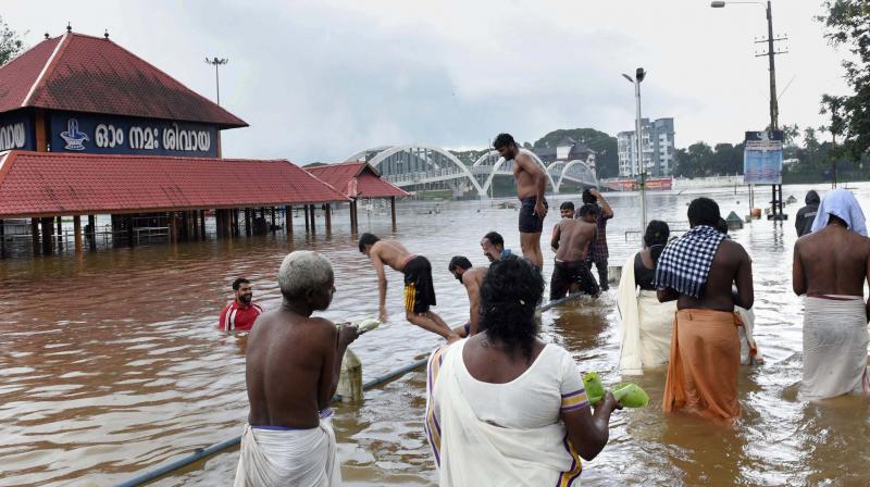 Devotees near the flooded Aluva Siva Temple in Kochi on Monday, as heavy rain continues to lash different parts of the Kerala state. (Photo: PTI)