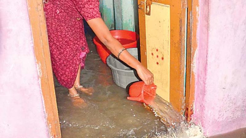 A woman drains water from her house, after city received heavy rainfall on Sunday. There was water  stagnation in Kargil Nagar, Rajaji Nagar and other surounding areas in Tiruvottiyur. (Photo: DC)