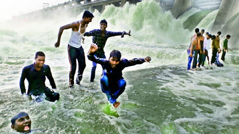 Youngsters frolic in water close to the crest gates of the Musi project at Suryapet on Tuesday, even as water gushes from the opened gates. (Photo: DC)