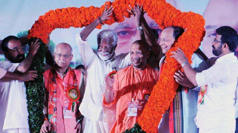 Uttar Pradesh chief minister Yogi Adityanath being garlanded as he joined Janaraksha Yatra led by Kummanam Rajasekharan on Wednesday. Union minister of state for finance Shiv Pratap Shukla (extreme left) looks on.  (Photo: DC)