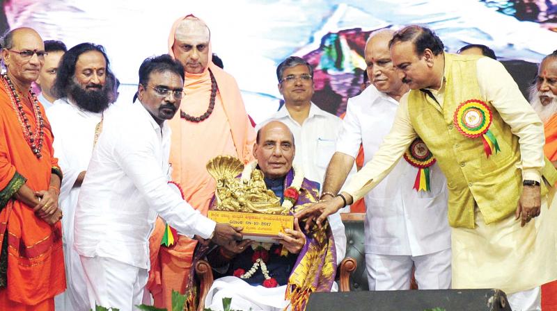 Union Home Minister Rajnath Singh being felicitated as Art of Living Founder Sri Sri Ravishankar during a programme held to celebrate the 9th anniversary of Vishwakarma Mahasabha at Palace Grounds in Bengaluru on Sunday. (Photo: PTI)