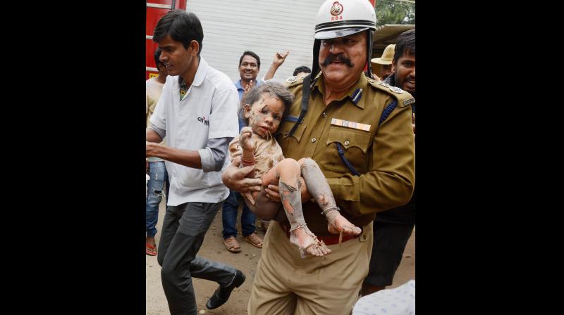 A fireman carries an injured rescued after a building collapsed due to a suspected cylinder blast at Ejipura area in Bengaluru on Monday. (Photo: PTI)